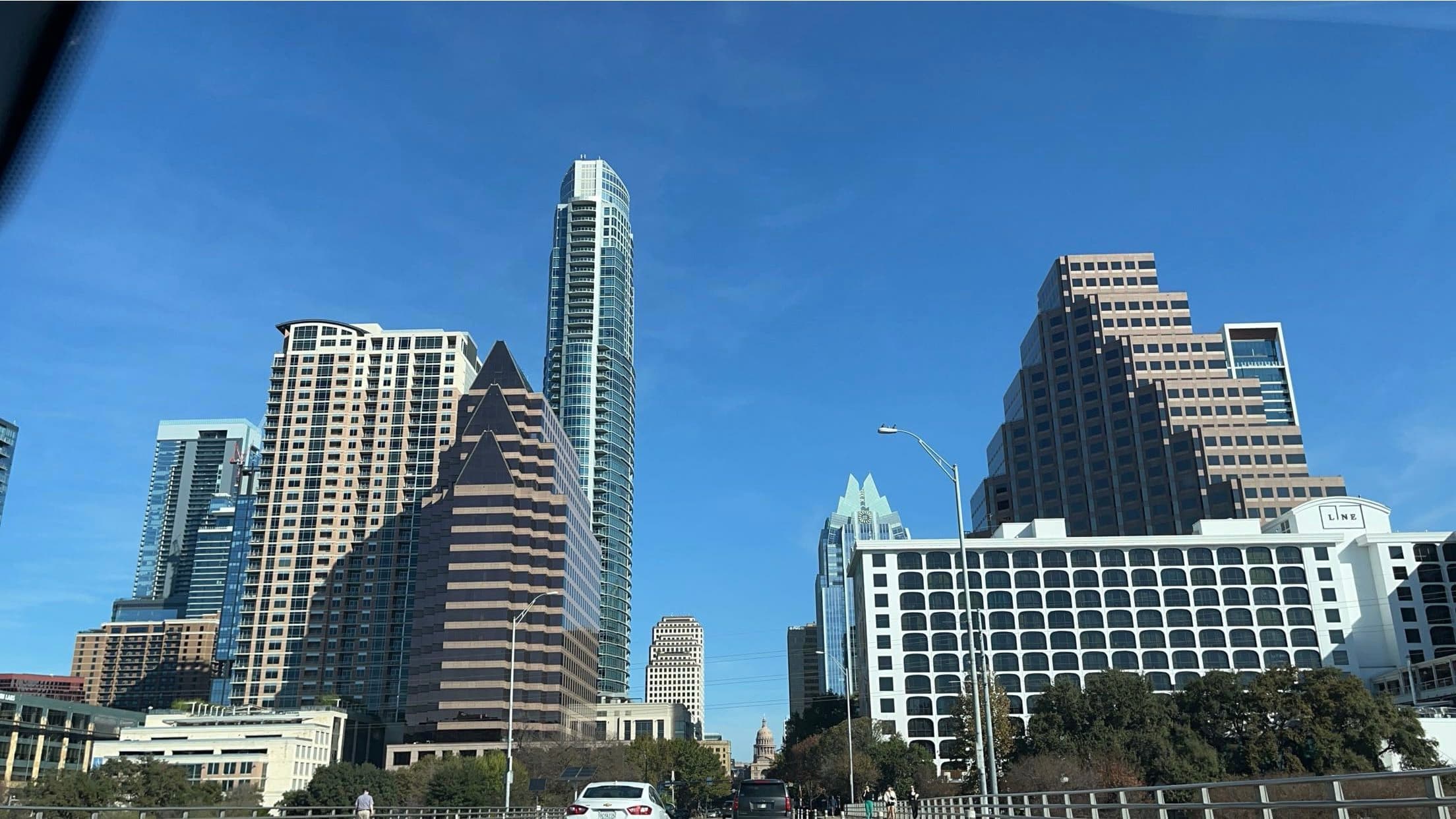 Modern skyscrapers of the Austin skyline rise against a clear blue sky from a bridge.