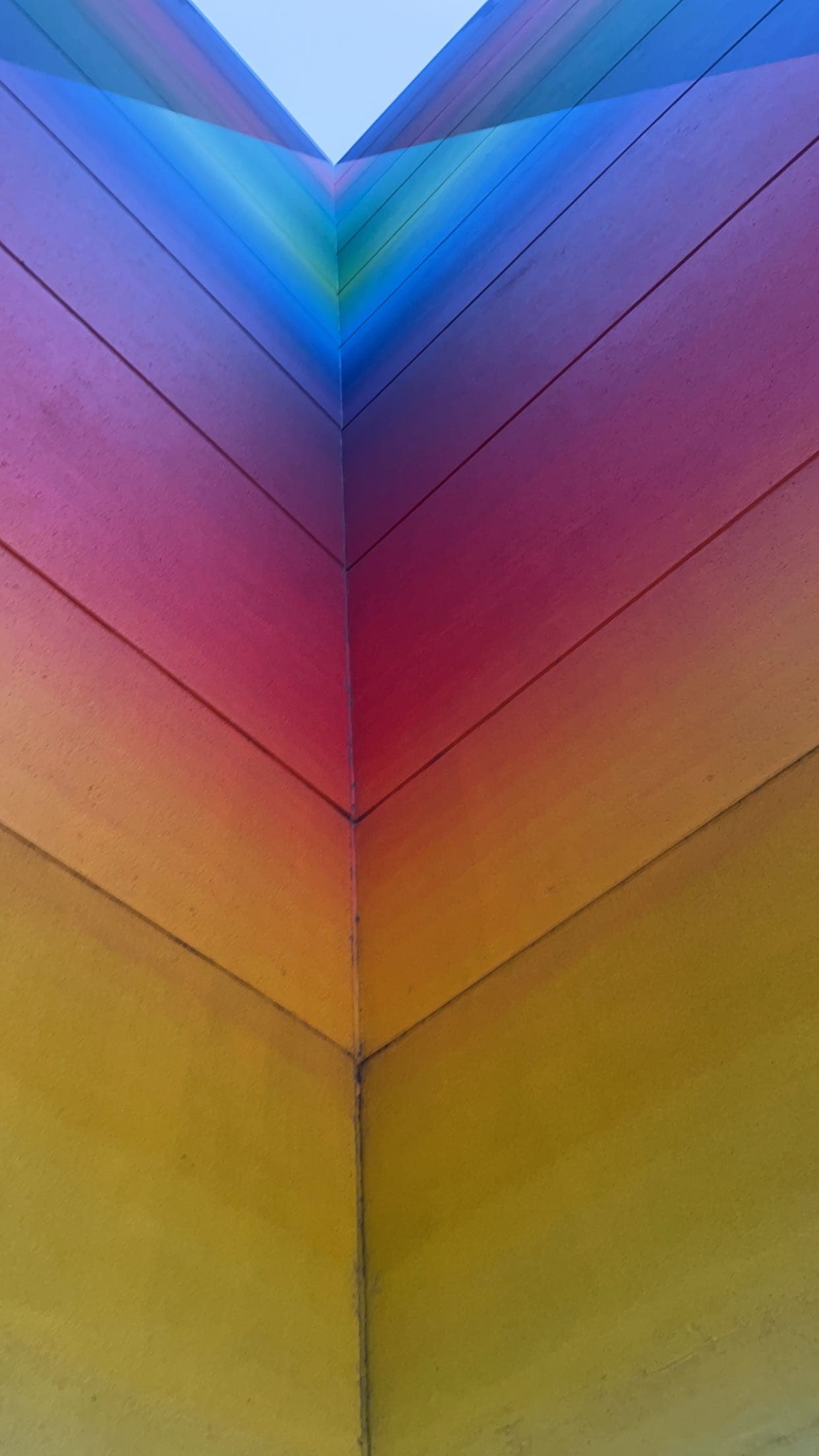 Vibrant rainbow-colored building corner with horizontal panels transitioning from yellow to deep blue.